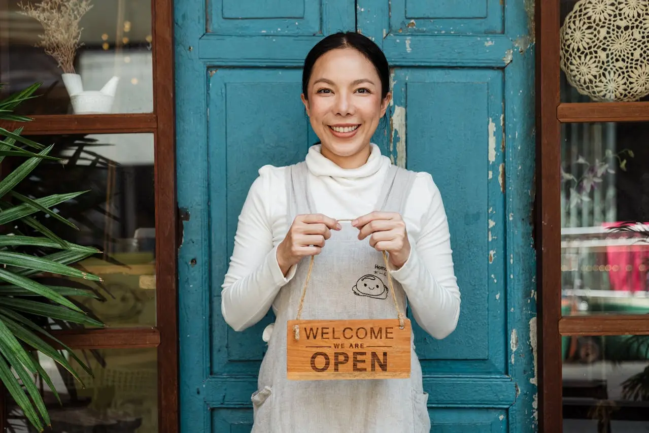 small business owner hold open sign while smiling